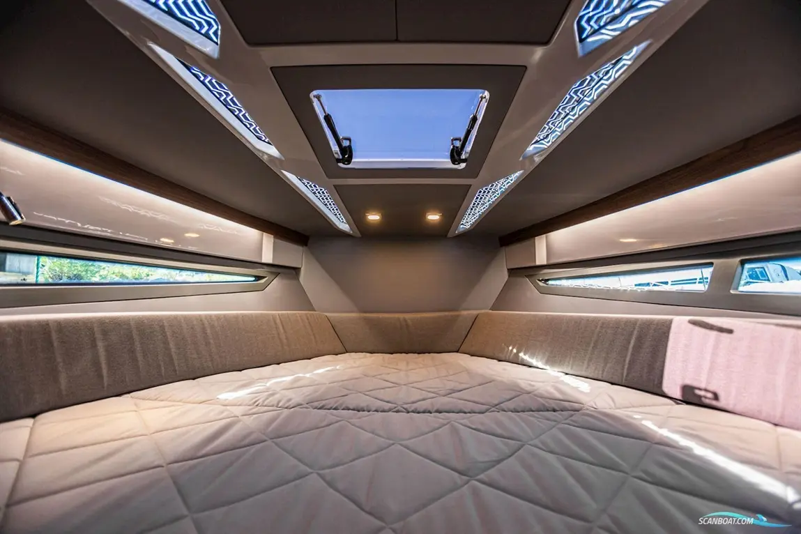 Modern boat cabin interior featuring a spacious bed, minimalistic design, and large windows for natural light.